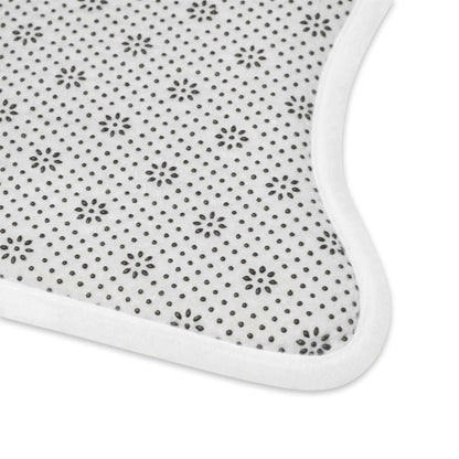 Close-up of a baby bib with a white background, black polka dots, and floral patterns along with a white border.