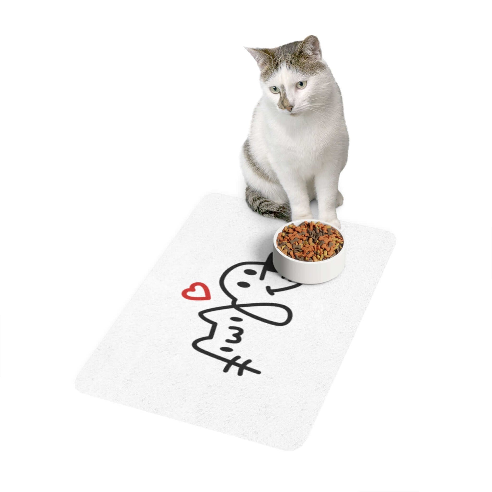 Cat sitting beside a bowl of food on a cute mat with a heart and abstract design.